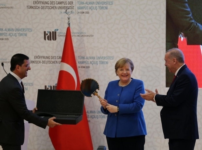 Merkel hediyeyi kaldrarak salondakilere gösterdi.