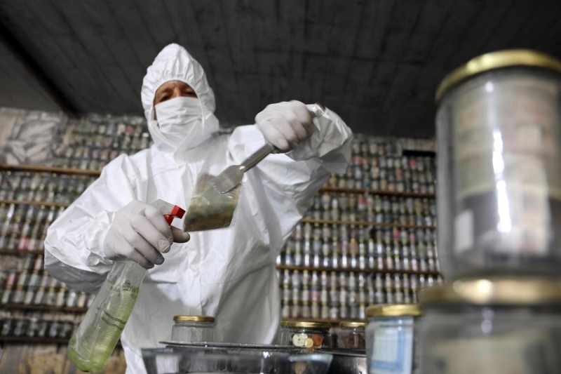 <p>Koruycu tulum giyip, maske ve eldiven takan Esat Kaplan, cmbz ile paralar tek tek cam fanusun ierisindeki dezenfekte ilacnda bir sre bekletti ve ardndan kavanozlara yerletirdi.</p>