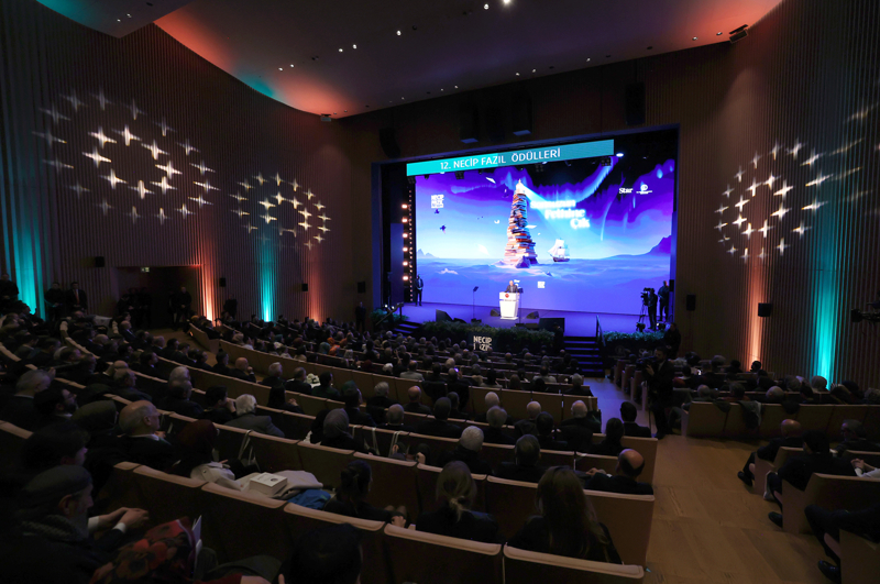 <p>Cumhurbaşkanı Erdoğan, Kısakürek'in bilhassa 1970'lerin sokaklara kadar sirayet eden karanlık ve kaotik atmosferinde kendine bir çıkış yolu arayan gençliğe istikamet çizdiğini, özgüven aşıladığını, tarih ve benlik şuuru kazandırmış bir kişi olduğunu belirterek, 'Pazarlıksız bir imanın, tefekkür ve dava bilincinin sancaktarı olan Büyük Doğu idealini genç gönüllere gergef misali işlemiştir. Merhum Necip Fazıl'ın çilesini çektiği, fikir ve aksiyon tohumlarını ektiği gençlik, hamdolsun bugün meyveye durmuştur. Türkiye Yüzyılı ülkümüze omuz veren, ülkemizin yarınlarını inşa eden gençlik, işte bizimle buradadır. Savunma sanayiinden siyasete, spordan kültür ve sanata, hayatın her alanında çağa mührünü vuracak, 'Kim var?' diye sorulduğunda sağına soluna bakınmadan 'Ben varım.' diye kükreyecek bir gençlik.' ifadelerini kullandı.</p>