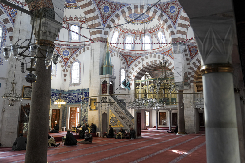 <p>Lacivert zemin üzerine beyaz celi sülüsle yazılmış Ayetel Kürsi kuşağı, mercan kırmızısı ve firuze detaylarla zenginleştirilirken sedef ve fildişi kakmalı kapı kanatları, mermer mihrap ve ince işçilikli minber klasik üslubun seçkin örnekleri arasında gösteriliyor.</p>