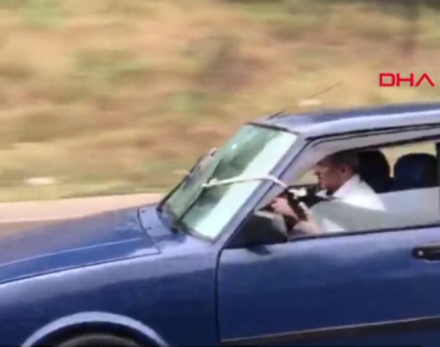 Grntlerde yamur altnda hzla ilerleyen otomobilin bozuk sileceklerinin arka koltukta oturanlar tarafndan iple ekilerek kontrol edildii grlyor.     